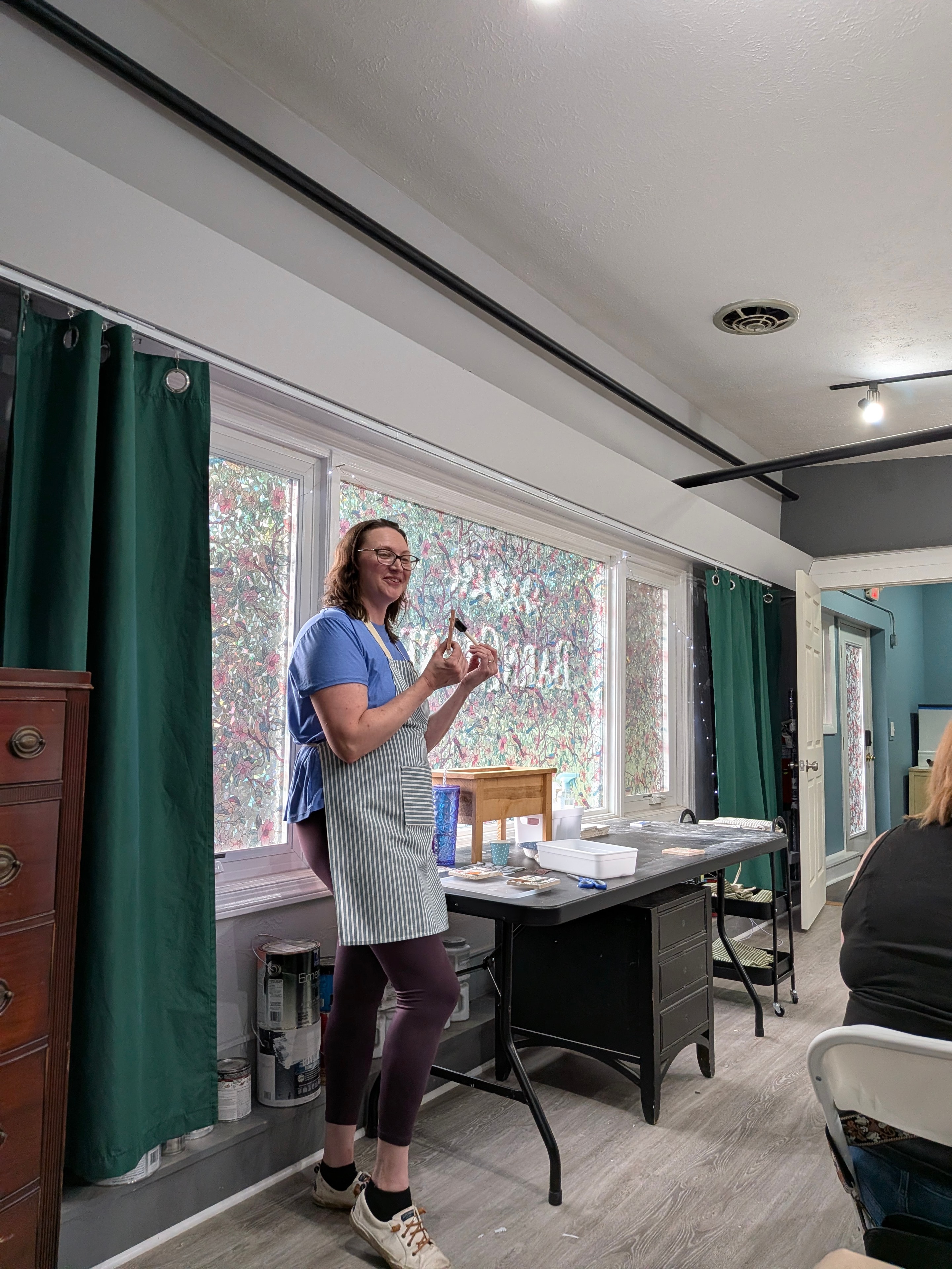 Studio instructor in apron demonstrating a craft technique to the class